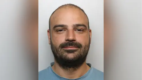 Thames Valley Police Adrian Dumitrache mug shot. He has very short brown hair and a short brown beard.