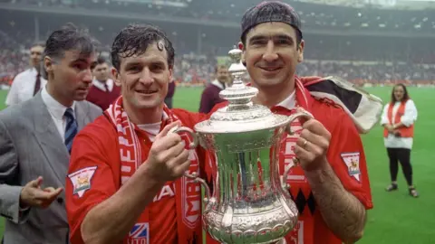 PA Media Mark Hughes and Eric Cantona holding the FA Cup