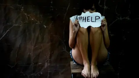 Getty Images Woman holding help sign