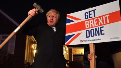 Getty Images Boris Johnson holding a hammer next to a 'Get Brexit Done' sign