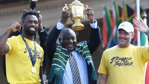 Getty Images Captain Siya Kolisi, President Cyril Ramaphosa and head coach Jacques Nienaber lift the trophy during the Rugby World Cup 2023 Springbok Trophy Tour in Pretoria at Union Buildings on November 02, 2023