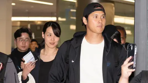 Getty Images Shohei Ohtani of the Los Angeles Dodgers and his wife Mamiko Tanaka are seen on arrival at Incheon International Airport on March 15, 2024 in Incheon, South Korea.