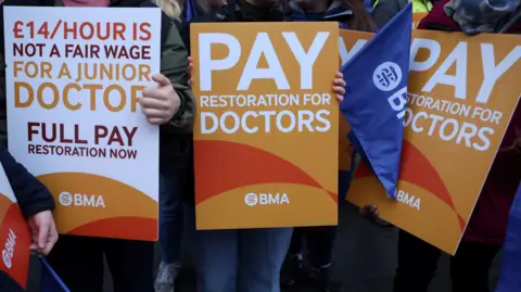 A group of signs being held by resident doctors striking last July in their calls for pay restoration