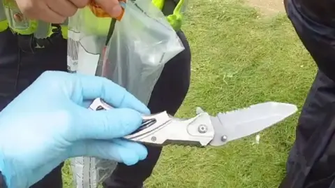A hand holding a knife found during a police stop and search.