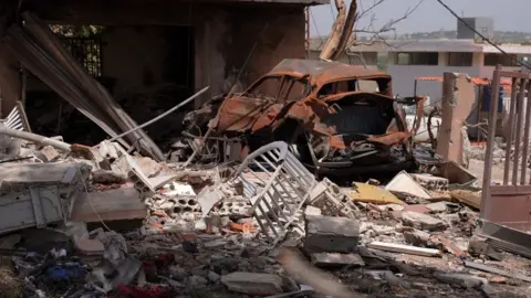 BBC A damaged and rusted car surrounded by debris