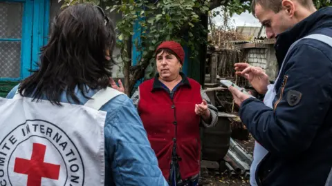Getty Images An ICRC representative talks with a Ukrainian woman in her village, situated on the line of contact between a Ukrainian government controlled area and non-government controlled area on October 26, 2018 in Luhansk, Ukraine.