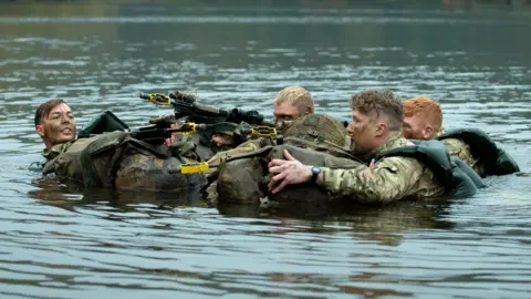 British Army Soldiers swim across a lake on a previous march