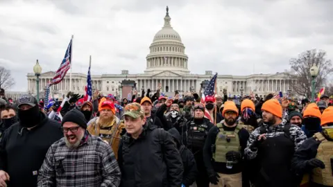 Getty Images Proud Boys, many wearing orange hats, along with other rioters outside the US Capitol on 6 January 2021