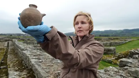 English Heritage Curator of Roman collections Frances McIntosh, holding an infant's feeding bottle