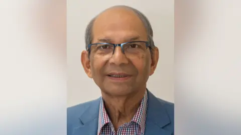 Rotherham NHS Foundation Trust A recent headshot of Dr Mondal. He wears glasses and a chequered shirt, and a blue blazer.