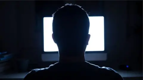 Getty Images Man sits in front of computer