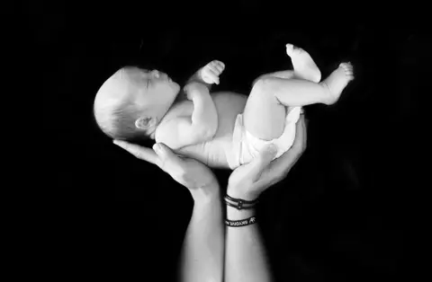 Chris Fawcett Holding a month old baby