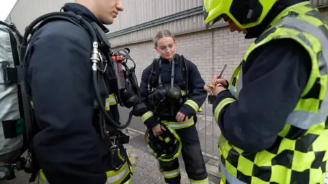 Macy Barker watches as a firefighter makes notes