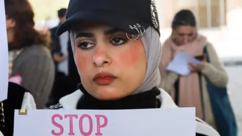 Reuters A woman holding a sign saying 'stop'