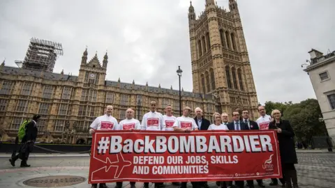 Getty Images Workers from the Bombardier factory in Belfast hold a banner to highlight their situation