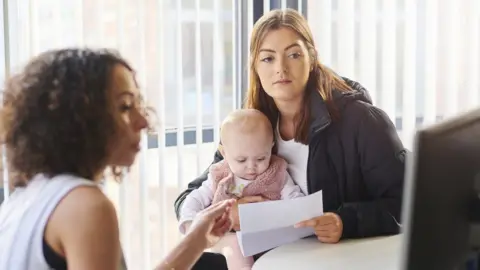 Getty Images Woman and baby with a benefits officer