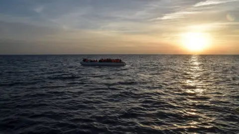 Getty Images Migrants and refugees sit on a rubber boat before being rescued by the ship Topaz Responder run by Maltese NGO Moas and Italian Red Cross off the Libyan coast in the Mediterranean Sea, on November 5, 2016.