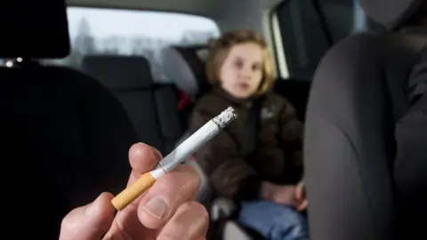 CLARK AND COMPANY/GETTY IMAGES Someone smoking in a car with a child in the back seat