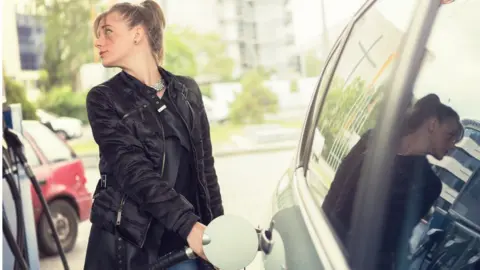 Getty Images Woman refuelling car