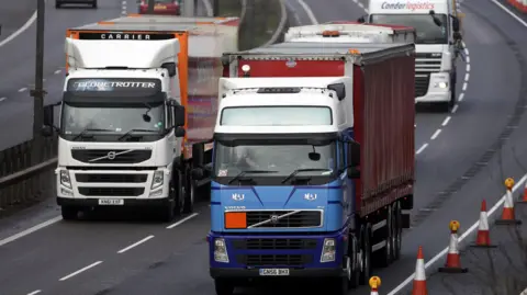 Getty Images Three lorries can be seen face on driving down a dual carriageway. Two of the lorries are just about side by side, with another following close behind. 
