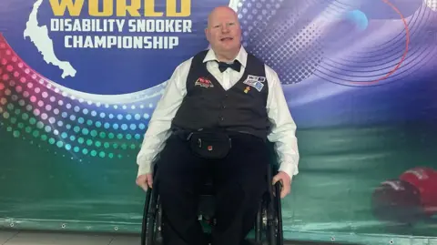 Gary Swift, who uses a wheelchair, dressed in a waistcoat and bow-tie at the World Disability Snooker Championship.