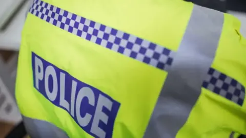 A general view image of the back of a police officer's hi-vis jacket, with POLICE written across the back of it.