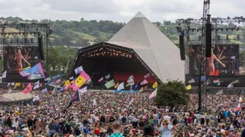 The pyramid stage at Glastonbury Festival. Thousands of people gather around the iconic tent.
