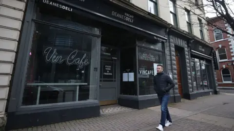 PA Media Man walks past a closed restaurant in Belfast in February 2021