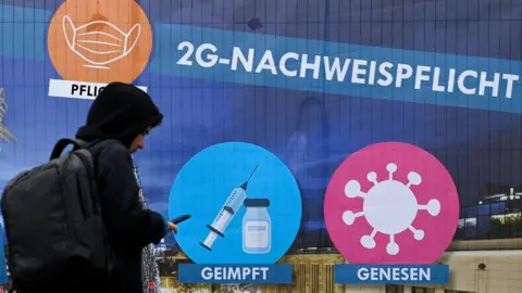 AFP A man walks past a placard which indicates the so-called 2G rule (vaccinated or recovered from Covid-19) for the Christmas market in the city of Dortmund, western Germany on December 1, 2021.