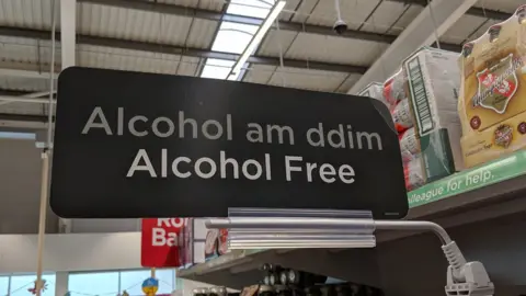 Twitter/@cwlcymro "Alcohol am ddim / alcohol free" sign in Asda