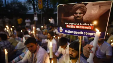 Getty Images Protesters hold candles at a peaceful protest, most are dressed in white in the twilight scene. A placard in the foreground, showing a black and white picture of Sidhu Moose Wala can be seen. It reads: "We demand justice for Sidhu Moosewala", with the subtitle Indian Youth Congress.