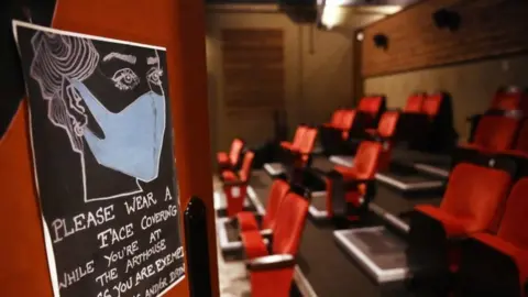 EPA A sign asking customers to wear a face mask inside an empty cinema auditorium with distanced seating in London