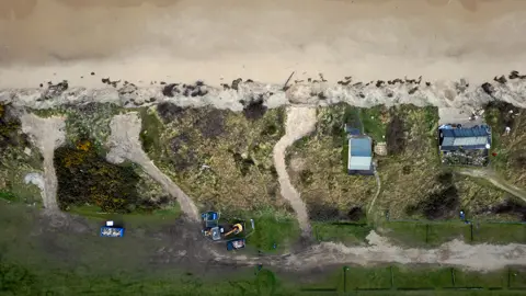 Martin Barber/BBC Aerial image of the Hemsby cliffs showing three gaps where properties once stood