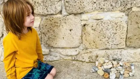 Harley kneeling next to a pile of rocks