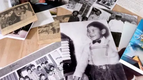 BBC Gabriel Schmidt looks at historic photos strewn across a table