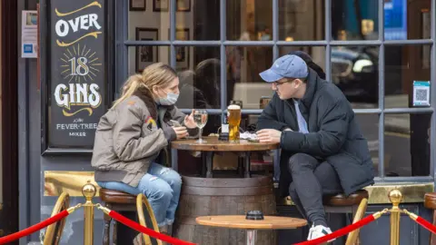 Getty Images People sitting outside the Cock and Lion pub in Marylebone in December 2020