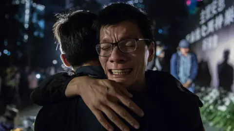 AFP A man cries after laying a flower during a vigil in Hong Kong on 10 November, 2019, in memory of university student Alex Chow