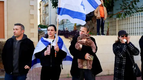 Reuters Israelis react as they gather in Rishon LeZion, central Israel, to watch the funeral procession for Shiri, Kfir and Ariel Bibas, who Israel says were killed in captivity after being taken hostage during Hamas's 7 October 2023 attack on southern Israel (26 February 2025)