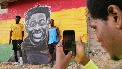 Getty Images Footballers having their photo taken infront of a mural of Christian Atsu at at Awudu Issaka Park, Tema, Ghana - Friday 24 February 2023
