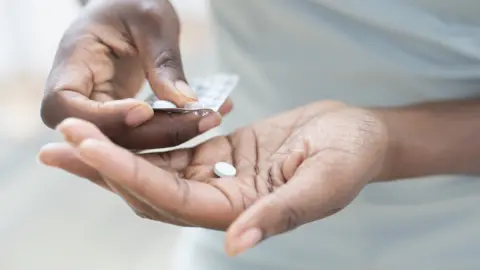 Getty Images Hand holding pills