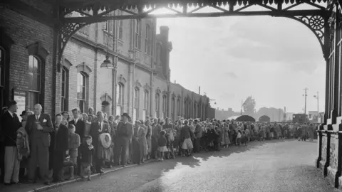 Historic England People queue at train station