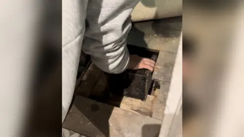 Madeline Goodwin Someone taking out a box from underneath the floor boards