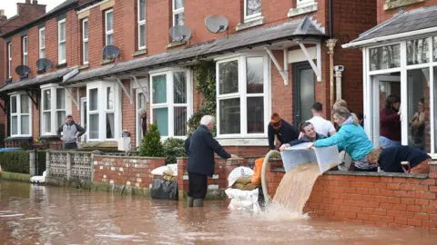 Getty Images People bail water out of flooded homes after the River Wye burst its banks in Ross-on-Wye, western England, on February 17, 2020,