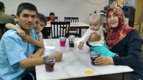 SUPPLIED Mamutjan Abdurehim with his two young children and wife Muherrem in a restaurant in Malaysia