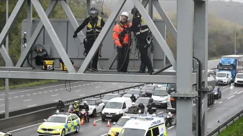 Rex Features Police officers remove a protester from a motorway gantry