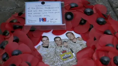 A wreath of poppies and an image of three soldiers and a Lest We Forget message