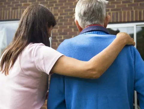 Science Photo Library Home carer with arm round disabled man's shoulders