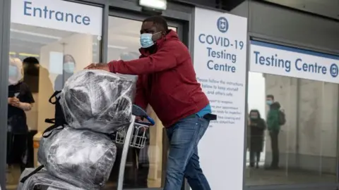 Getty Images A passenger walks past a novel coronavirus Covid-19 testing site