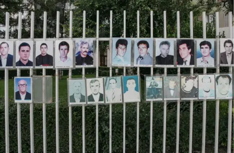 Chris Leslie A fence with photos of missing men attached to the railings