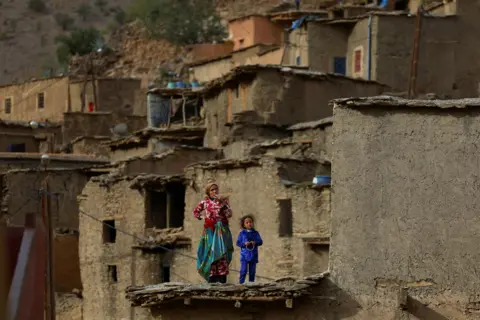 HANNAH MCKAY/Reuters People stand on a house, in the rural village of Azermoun, Morocco September 14, 2023
